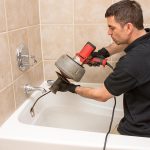 Clogged drain being cleared by a plumber