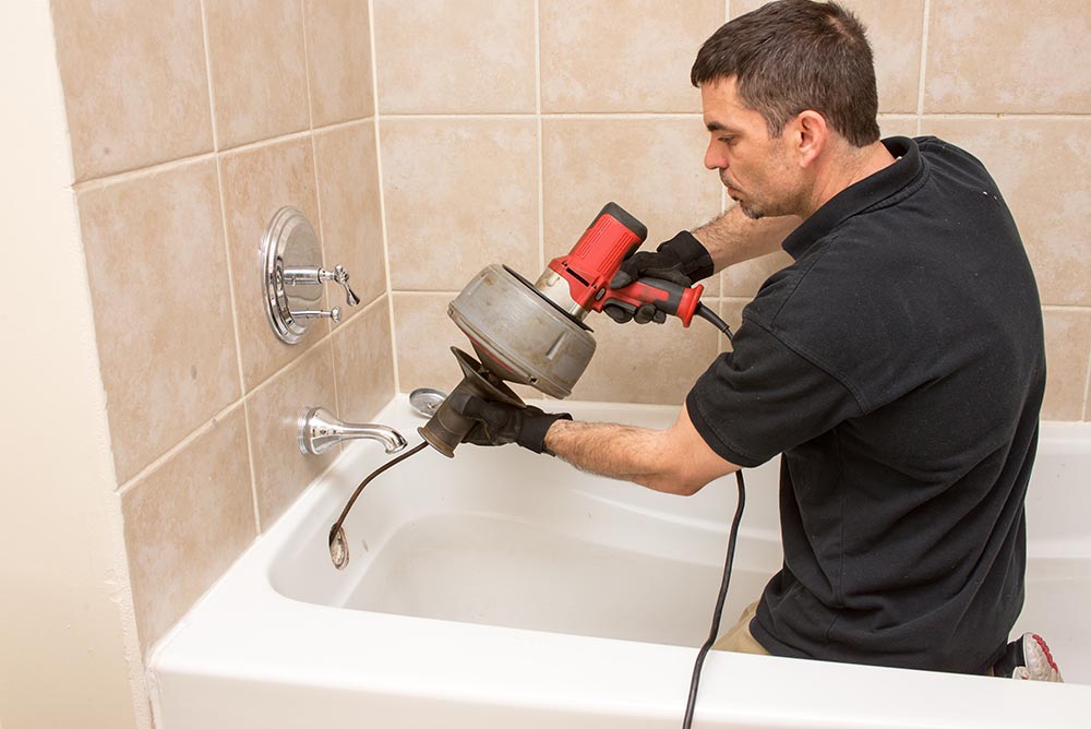 Clogged drain being cleared by a plumber