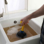 man using plunger to unclog sink drain
