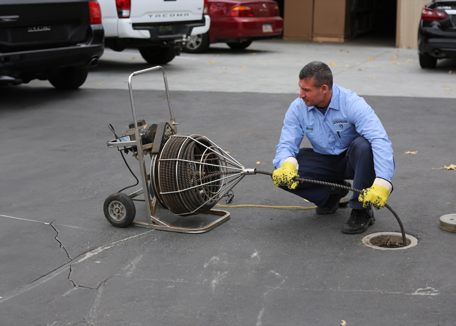 EJ drain technician feeding a professional drain-cleaning cable into a main line